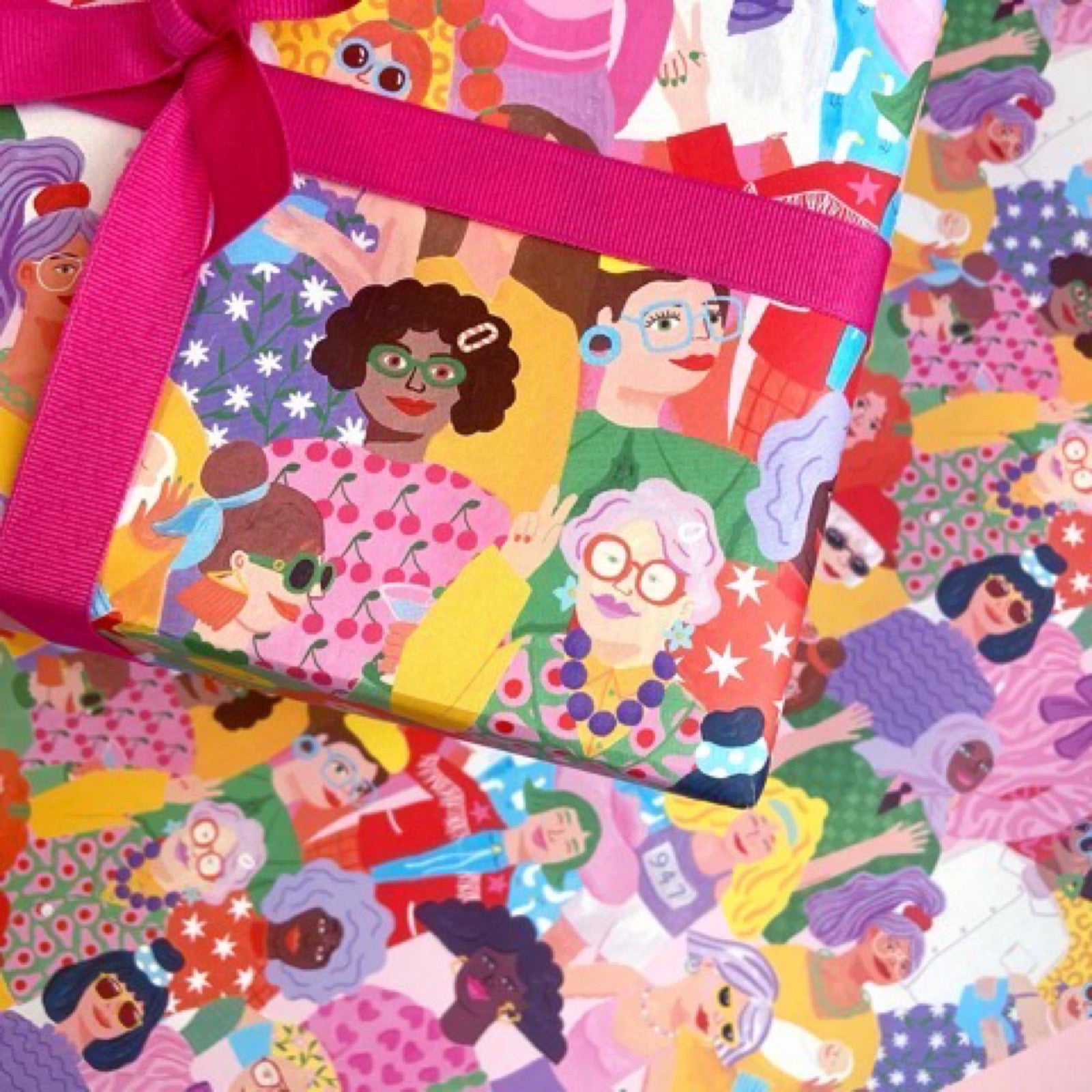 Wrapping paper featuring a lot of ladies in bright colourful clothes against a white background.