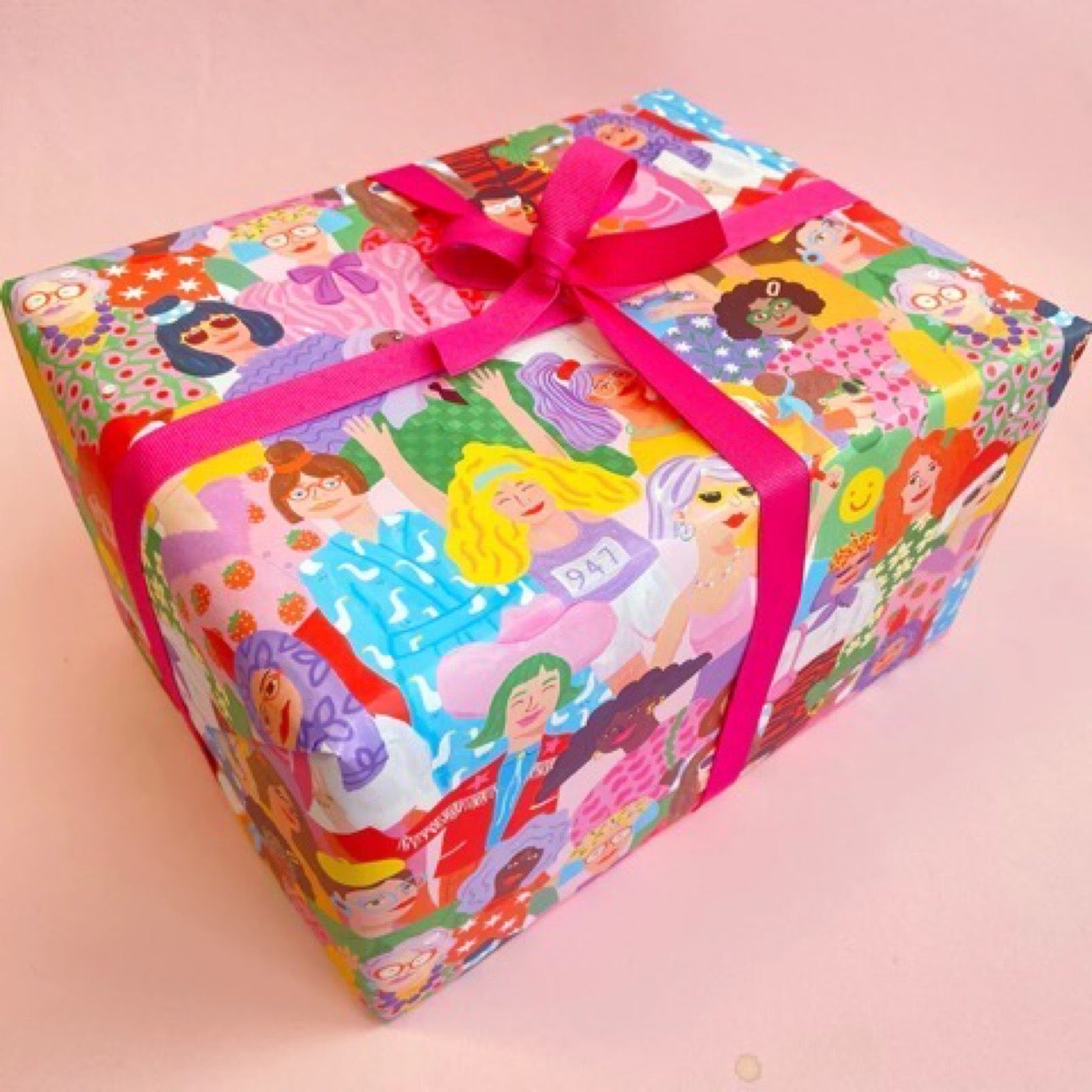 Wrapping paper featuring a lot of ladies in bright colourful clothes against a white background.