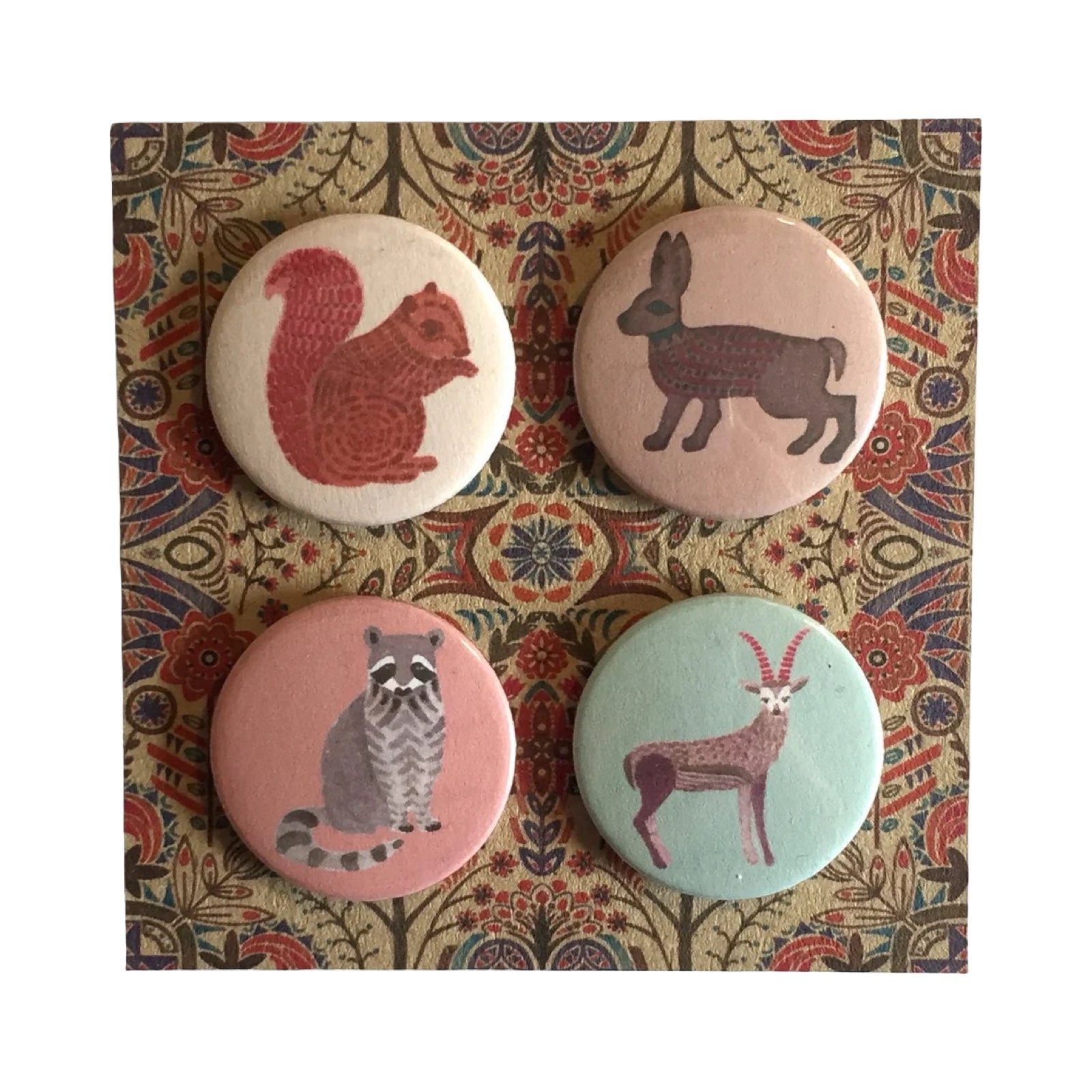 Four animal-themed badges on a patterned fabric background.