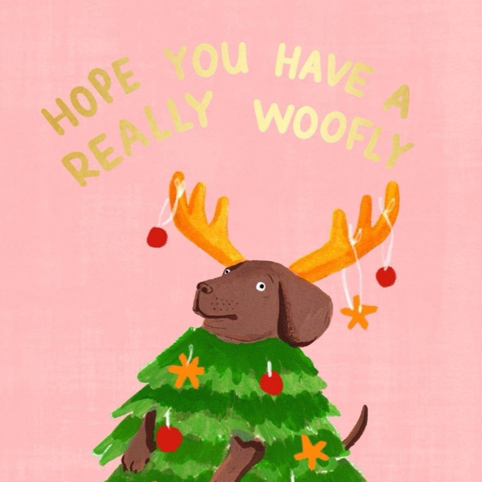 Dog in a Christmas tree costume with antlers and ornaments on a pink background with text.
