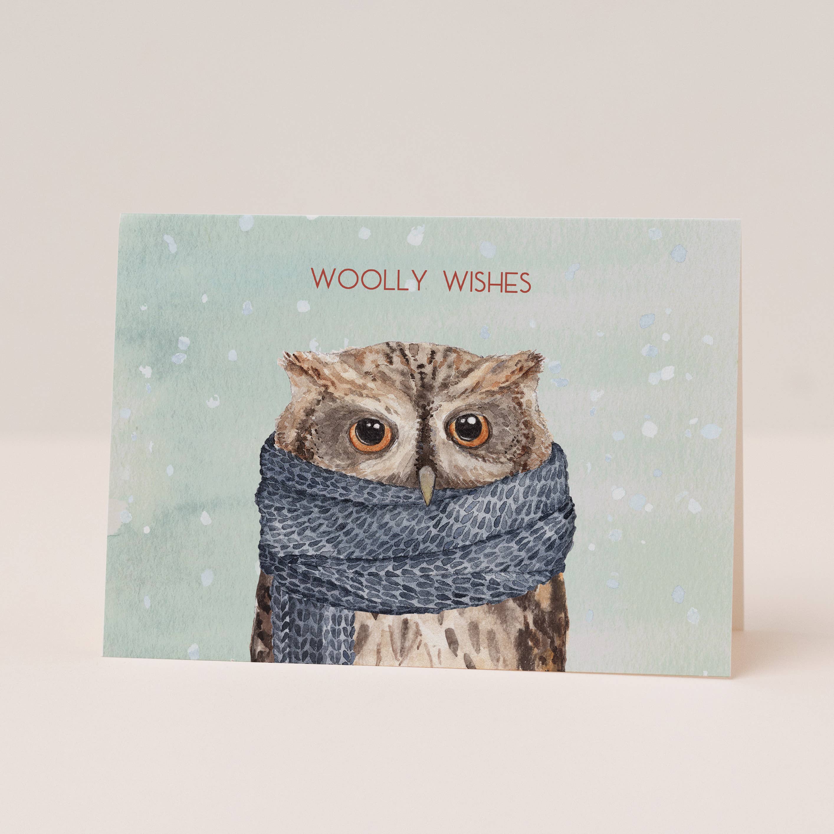 Card with an owl wearing a scarf and 'Woolly Wishes' text on a light blue background.