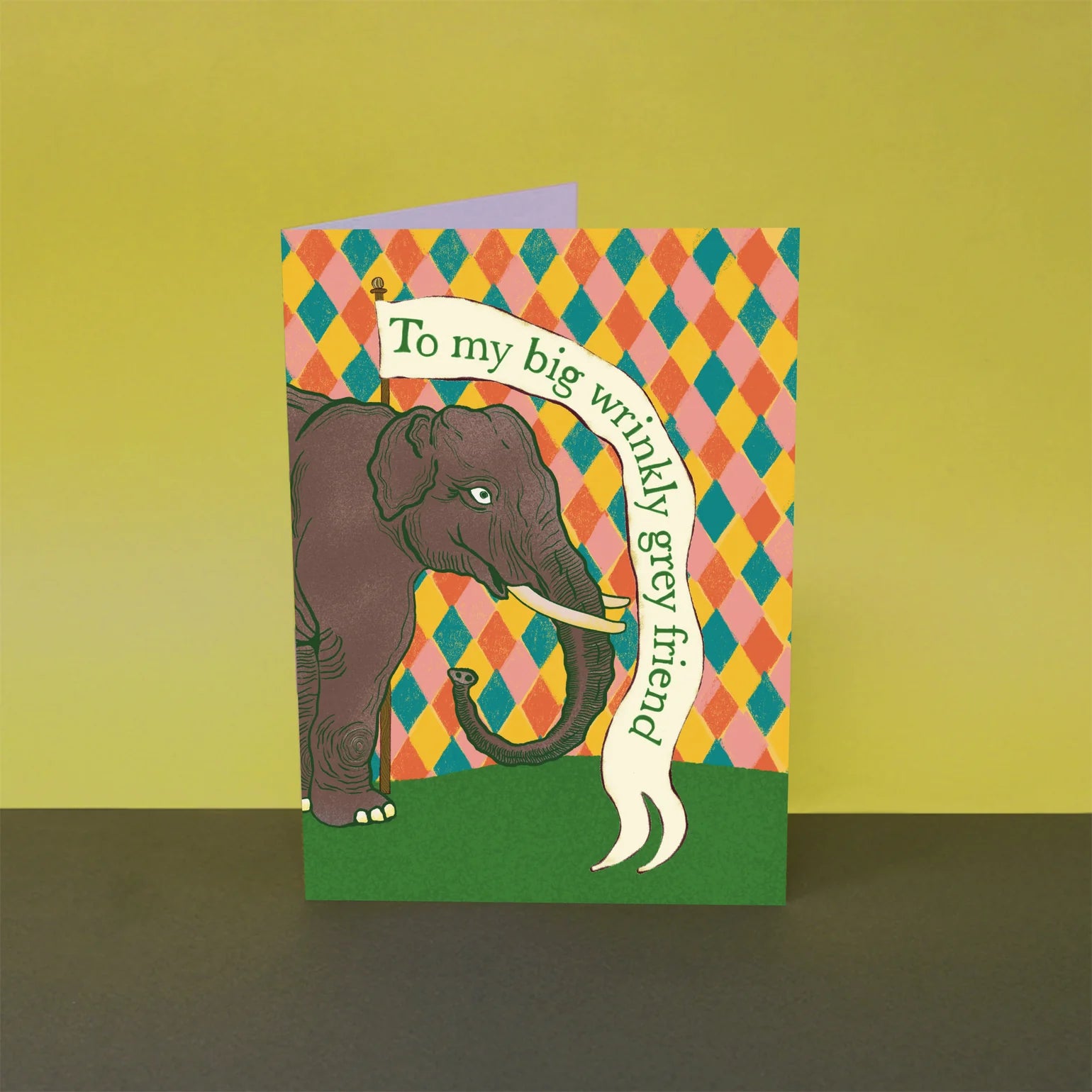 Greeting card with an elephant illustration and colourful pattern on a green background.