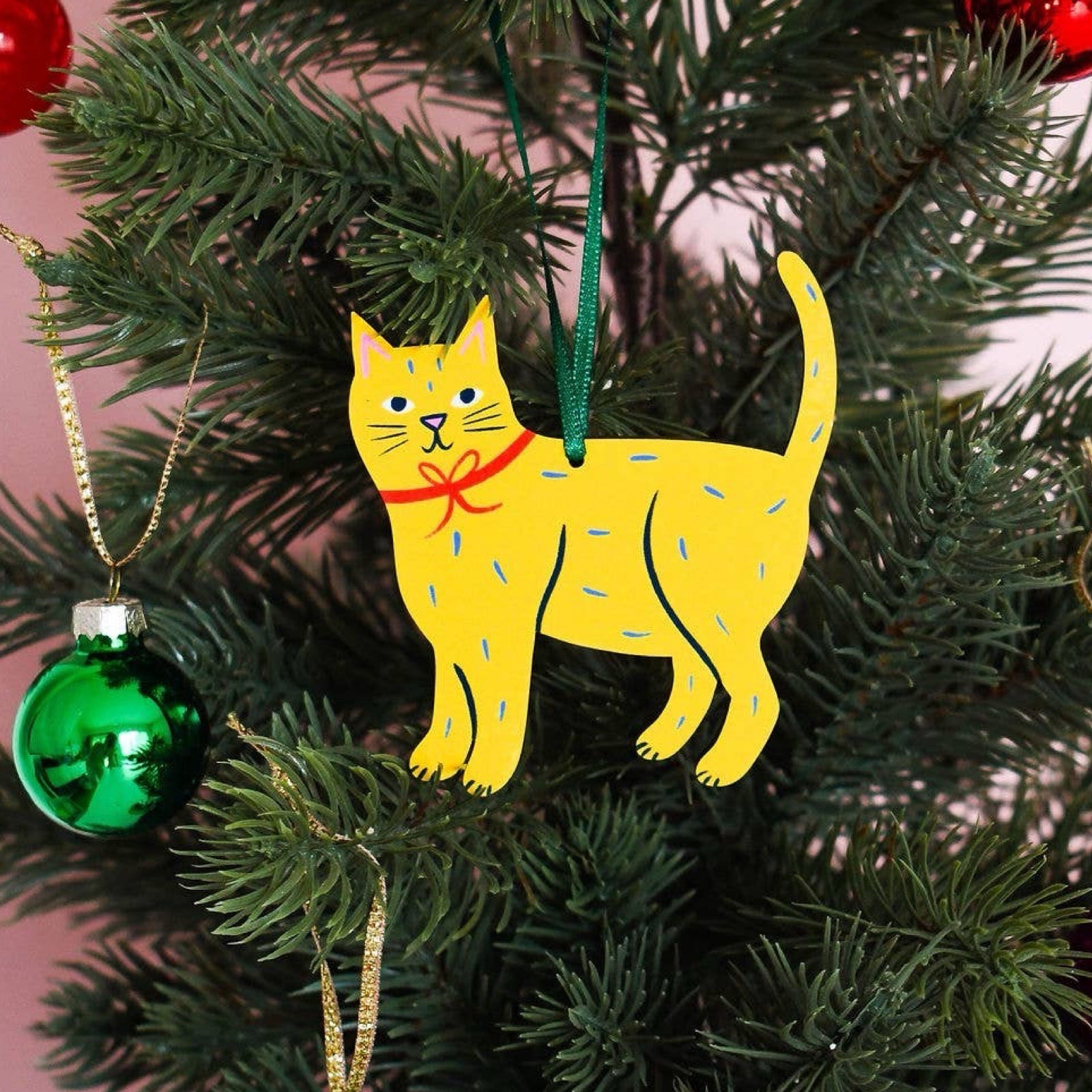 Wooden Christmas cat-shaped decoration in yellow with blue dashes on tree.