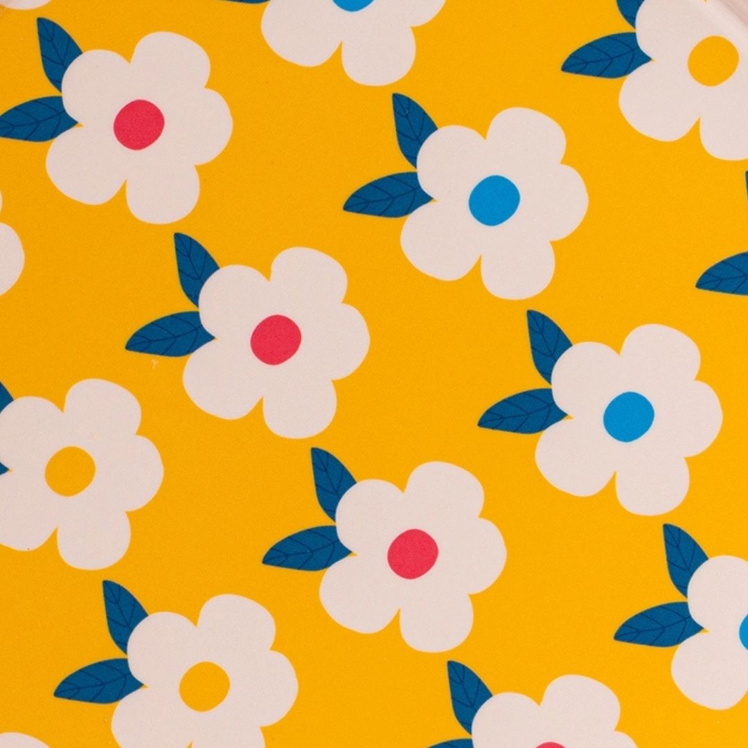 A close-up of a repeating floral pattern on a bright yellow background, featuring white flowers with blue leaves and centers in pink, blue, and yellow.