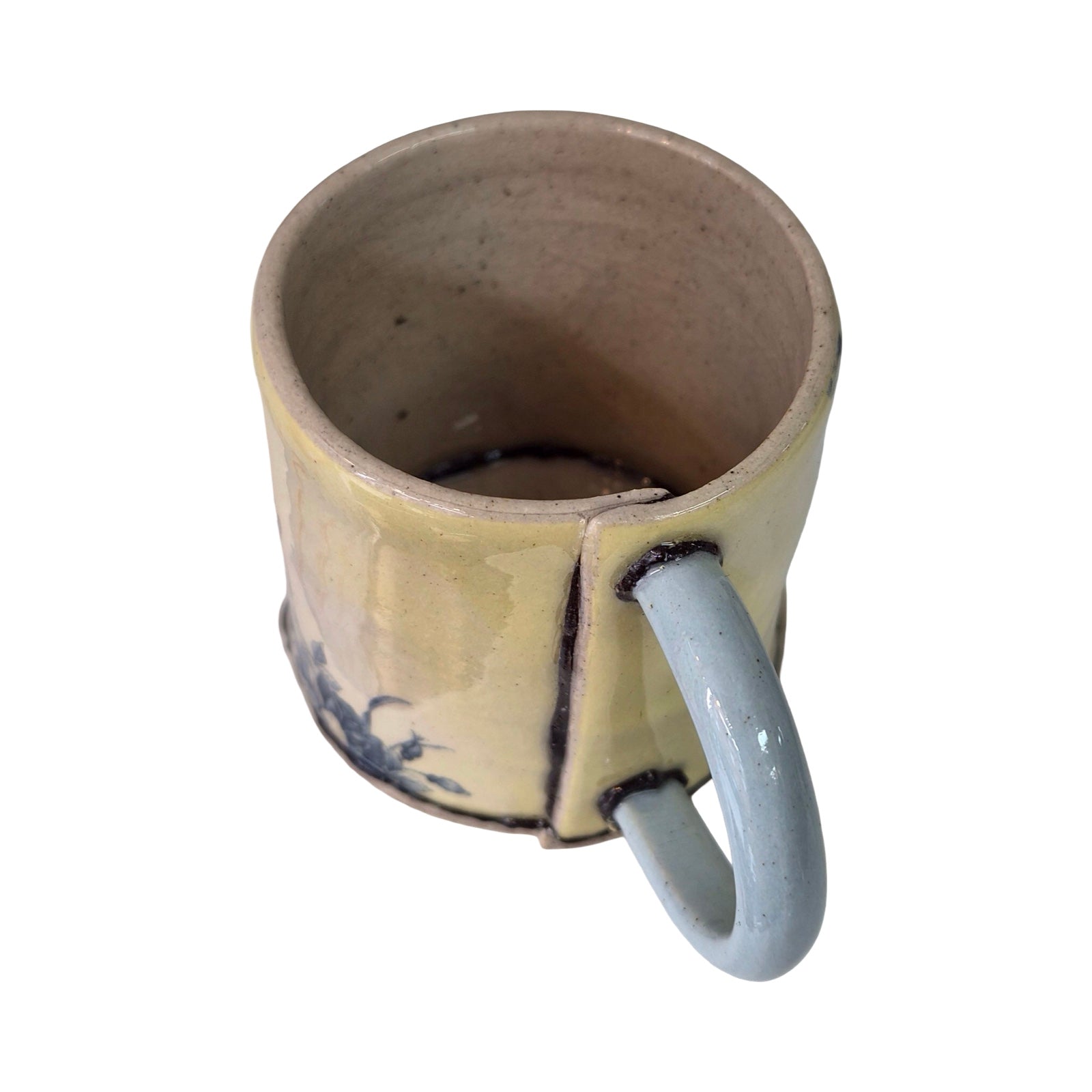Ceramic mug with a blue handle on a white background.