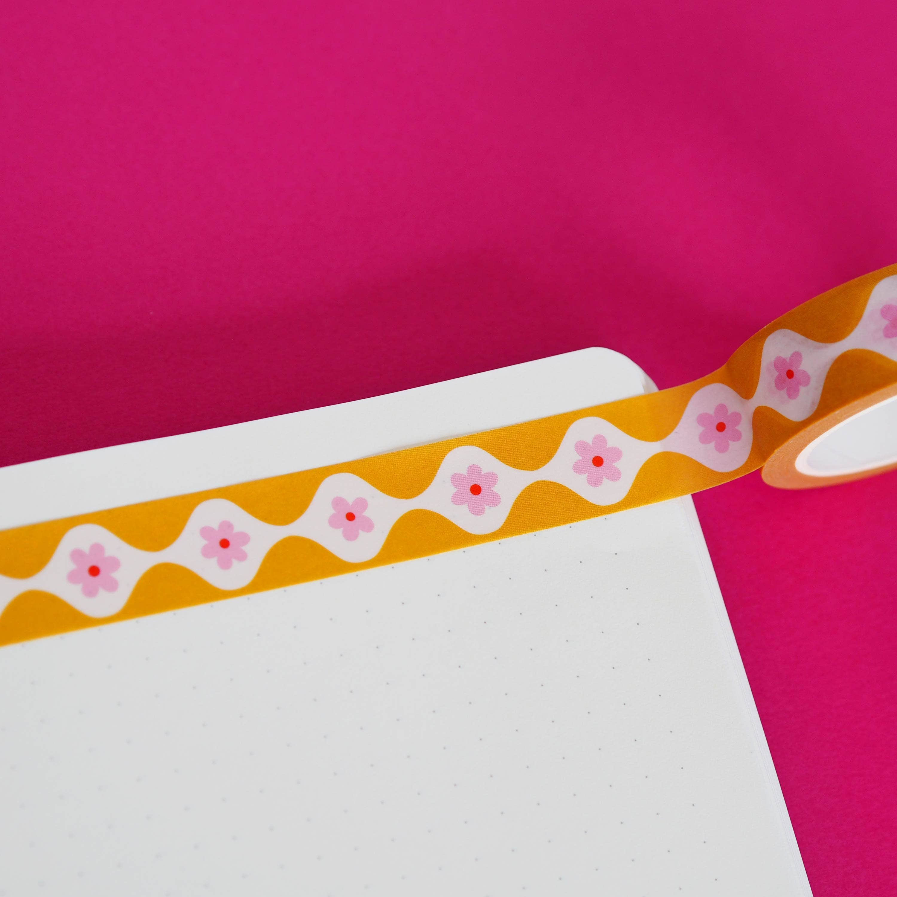 Decorative washi tape with floral pattern on a pink background.