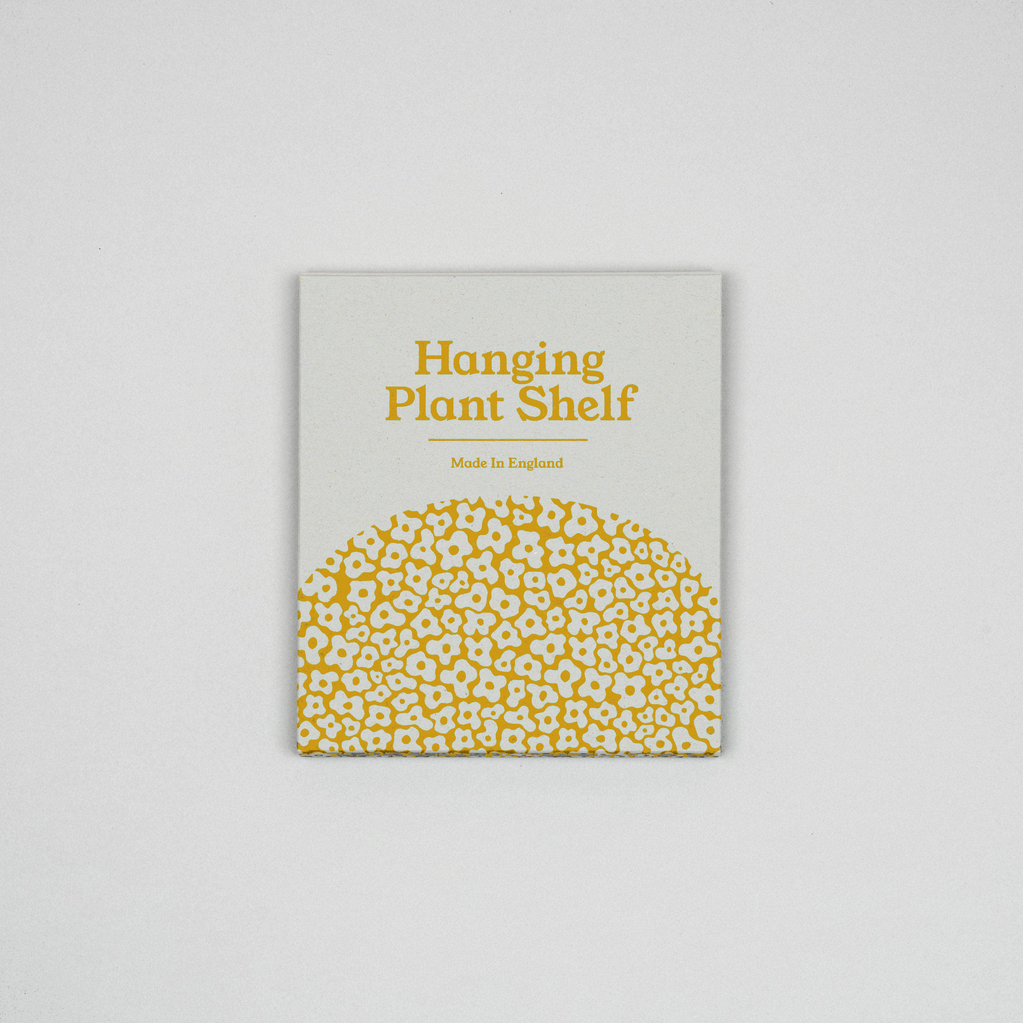 Product packaging for a hanging plant shelf with yellow text and pattern on a grey background.
