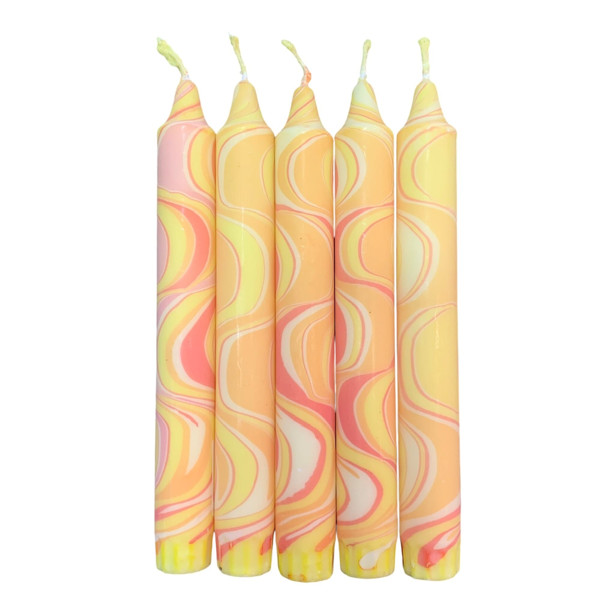 A row of 5 handmade dinner candles marbled in shades of yellow.