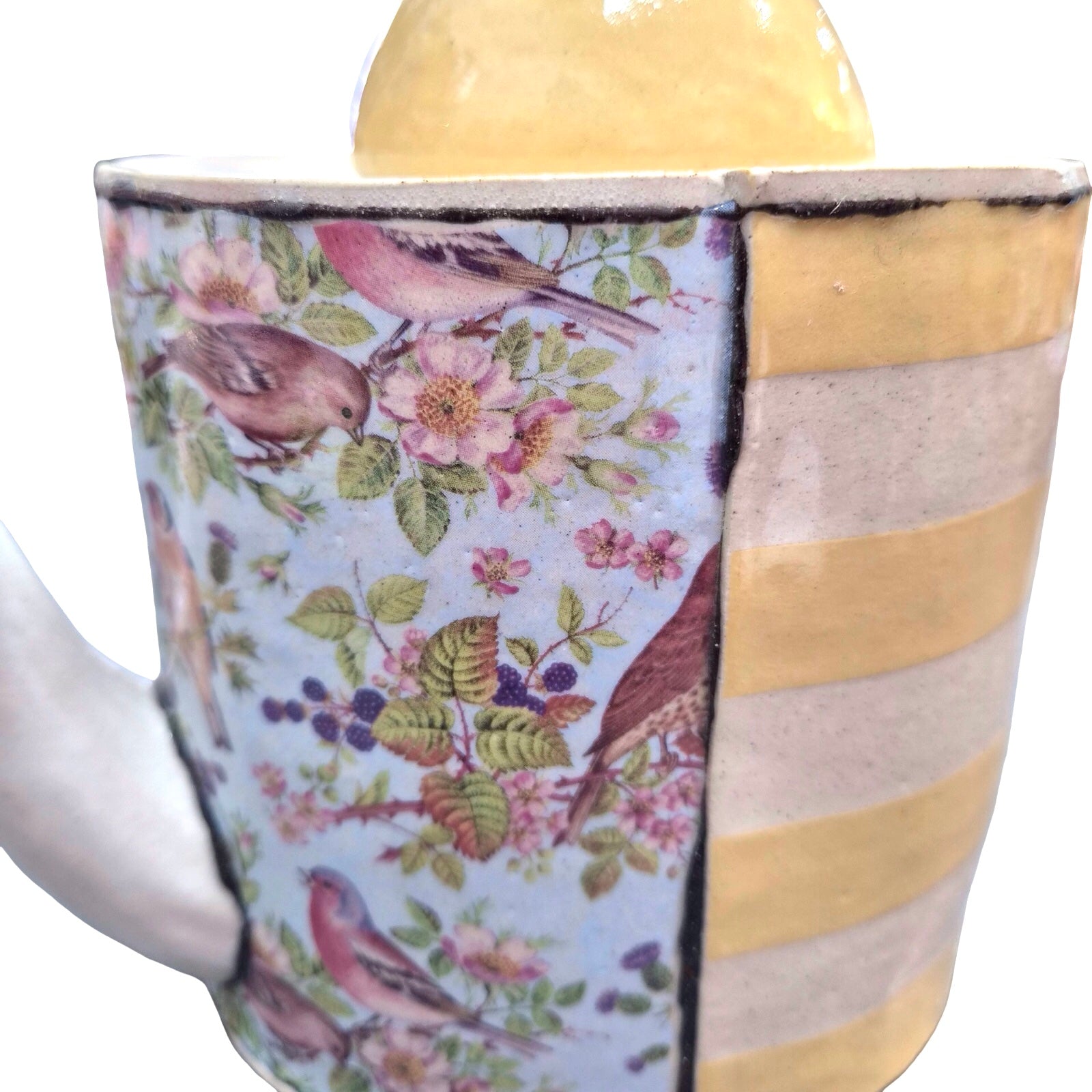 Ceramic teapot with floral and bird design on a white background.